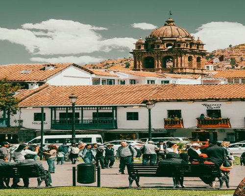 Sunny day in an Andean plaza in Cusco with locals resting on benches